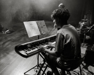 Black and white photo of student performing a song on the piano at Summer Sounds with SoundCheck 2024